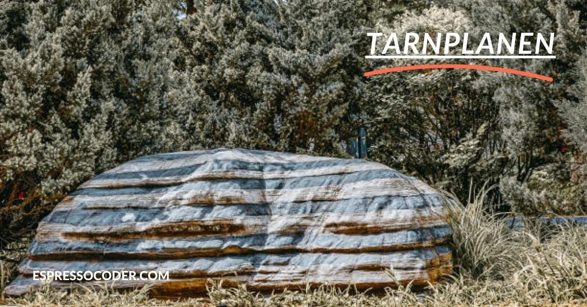 Woodland camouflage tarnplanen covering gear in forest terrain.