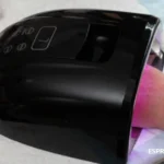 Nail technician using YWMLFZ cordless lamp during home visit manicure session.