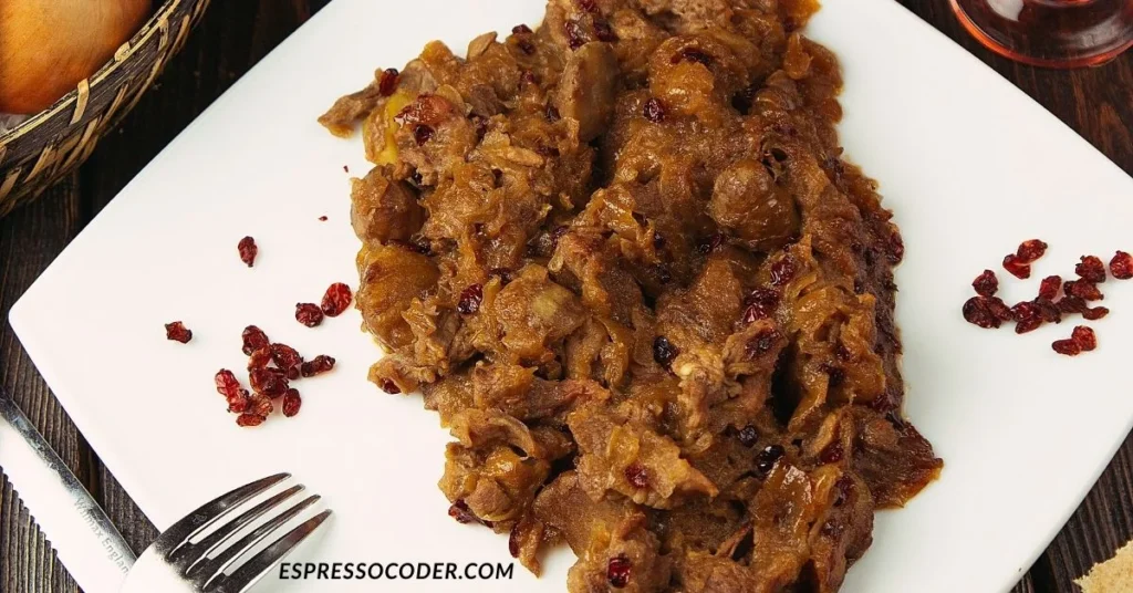 Traditional mulgipuder served with fried pork and onions on rustic wooden plate.